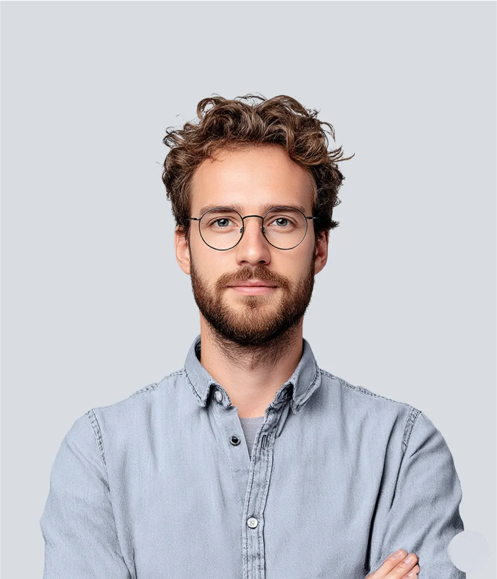 Portrait of a man wearing glasses and a light blue shirt, smiling slightly.
